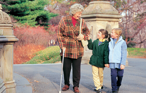 Patiente âgée marchant dans un parc accompagnée de deux enfants