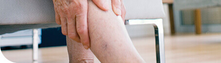 Mains d’un patient agrippant sa jambe