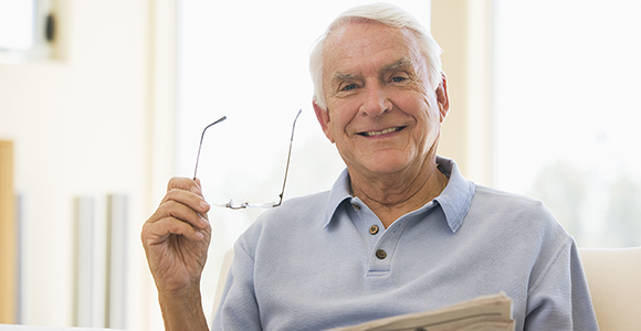 Patient holding a stack of papers and his reading glasses