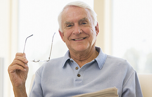 Patient holding a stack of papers and his reading glasses