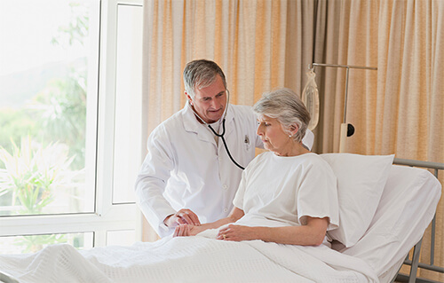 Patient in hospital bed with doctor by her bedside