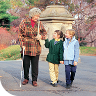 Older female patient walking in a park with two children