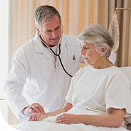 Patient in hospital bed with doctor by her bedside